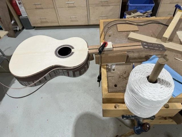 The binding strips on the front and sides of the guitar are getting ready to be glued