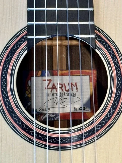 Close-up of an acoustic guitar's soundhole with a label inside that reads "Zarum guitarra de Arte Ana 2023 No. 001".