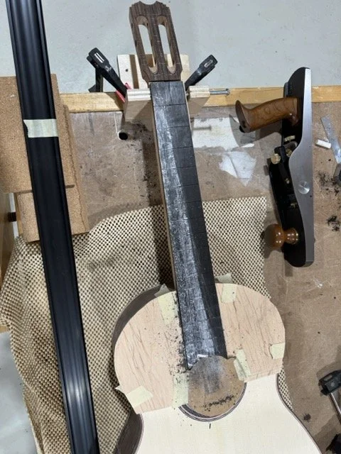 Using chalk and a hand plane to shape the fret board 