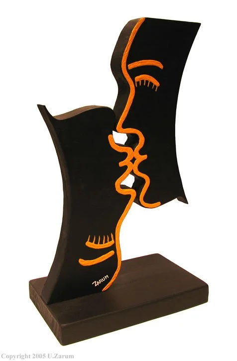 Zarum Statue titled 'Kissing" Black wooden sculpture featuring an abstract profile of a face, outlined in orange, on a wooden base.