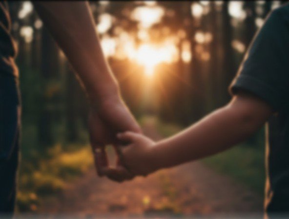 Two people holding hands along a forest trail during sunset.