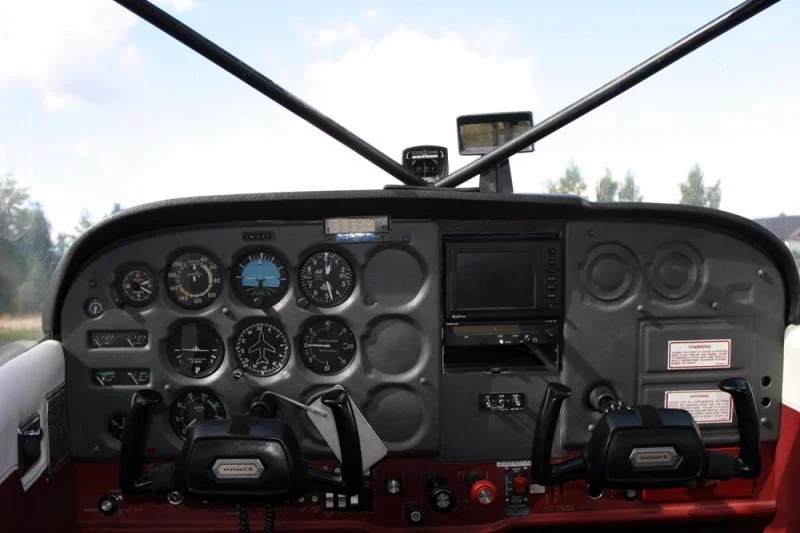 The cockpit of an airplane with various gauges, switches, and two control yokes.