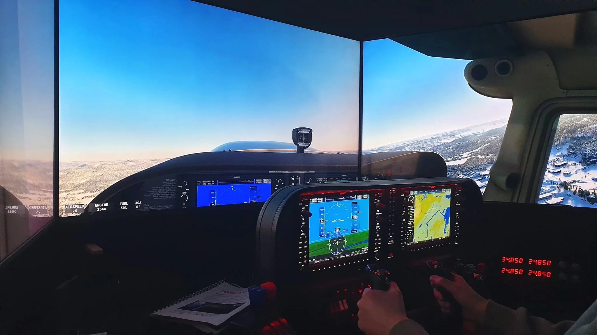 Inside the cockpit of a small aircraft, showing pilot controls, screens with navigation and altitude data, and a view of snow-covered mountains outside the windshield during daylight.