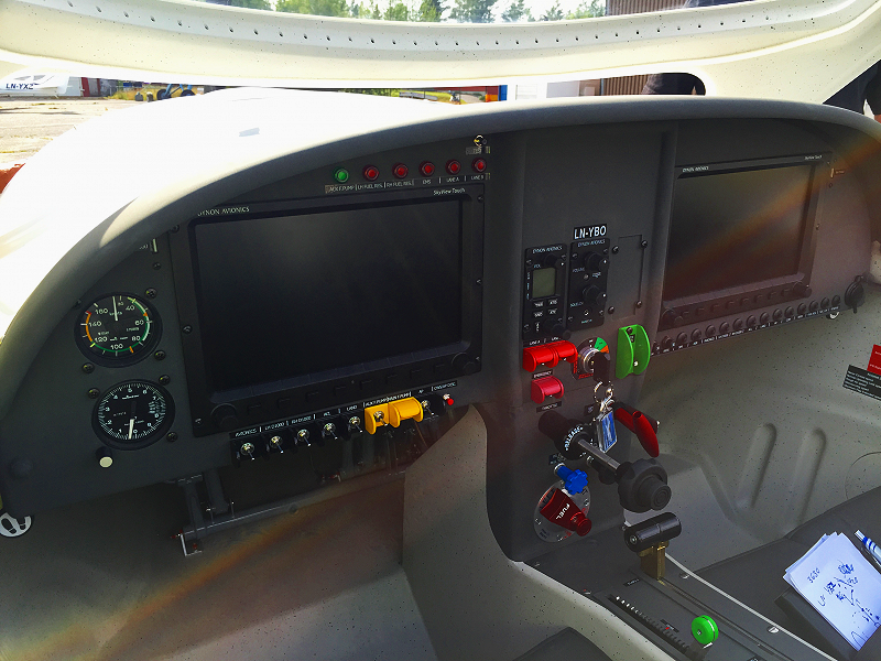 The cockpit of a small aircraft with two large digital displays, various switches, and gauges.