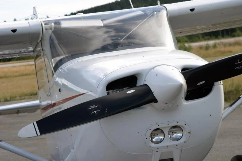 Front view of a small single-engine propeller plane parked on the tarmac.