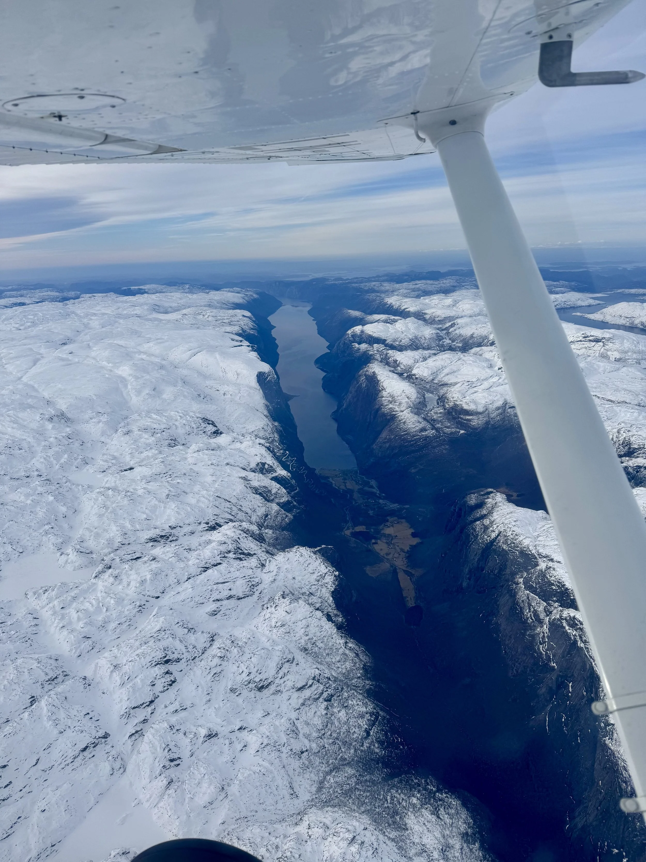 Flyfoto av en snødekt dal med en innsjø i midten, sett fra et fly i luften.