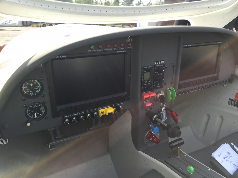 The cockpit of an aircraft with various instruments and controls, including a GPS screen, gauges, and communication equipment.