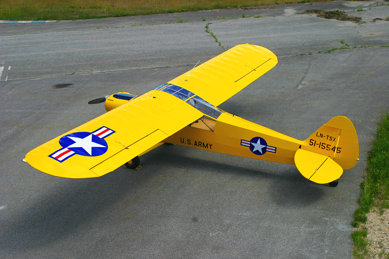 Yellow remote-controlled airplane with U.S. Army markings on a concrete surface.