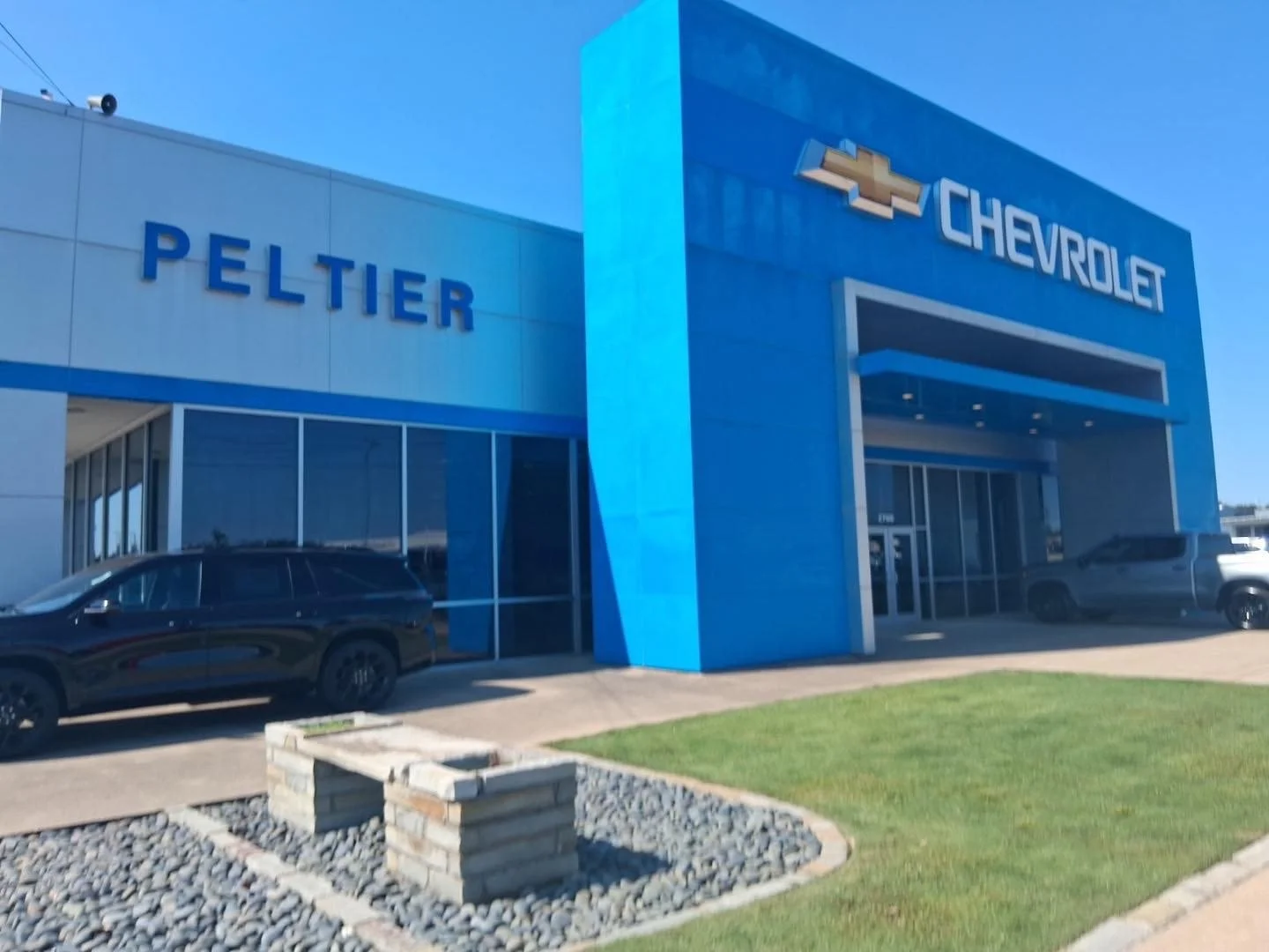 Exterior of a Chevrolet car dealership with blue building, Chevrolet logo, and cars parked outside