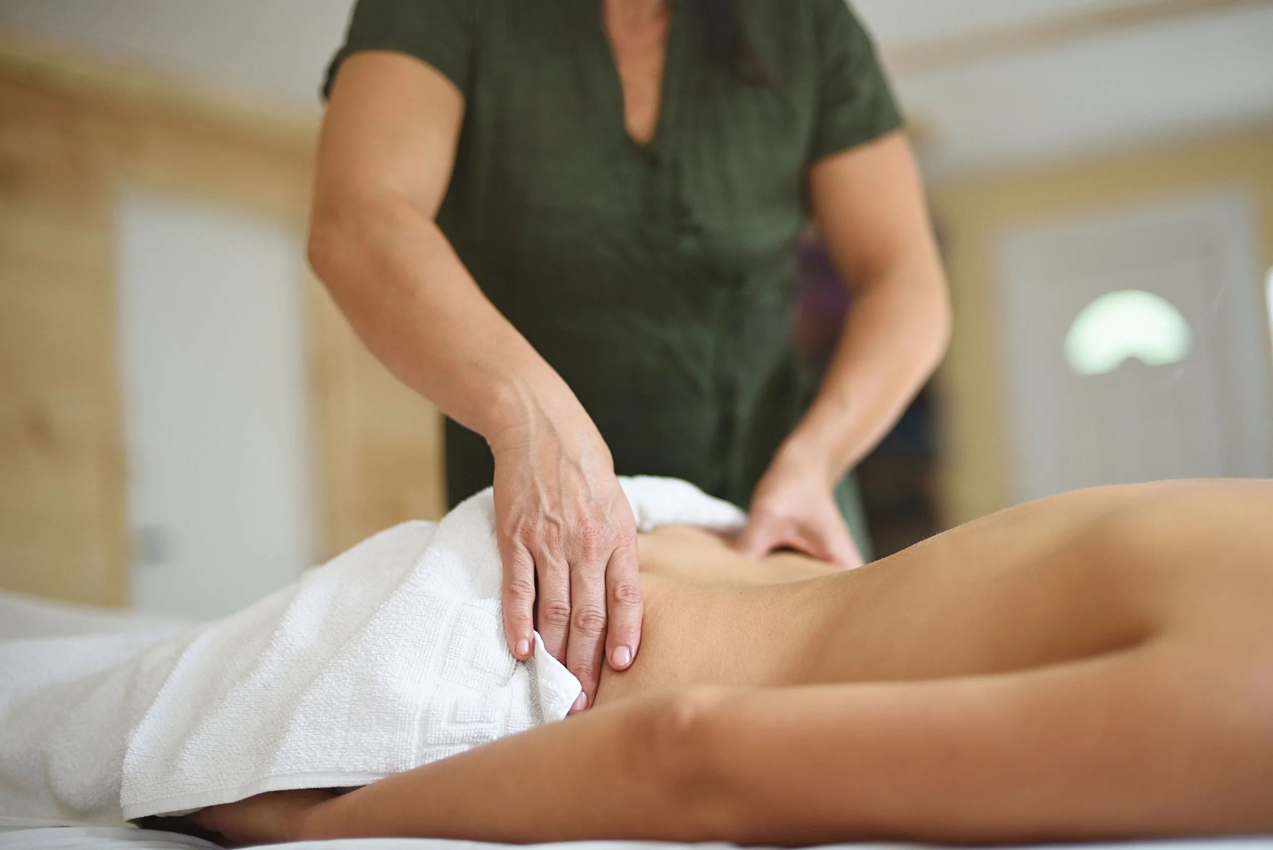 A person receiving a massage from a massage therapist in a wellness or spa setting.