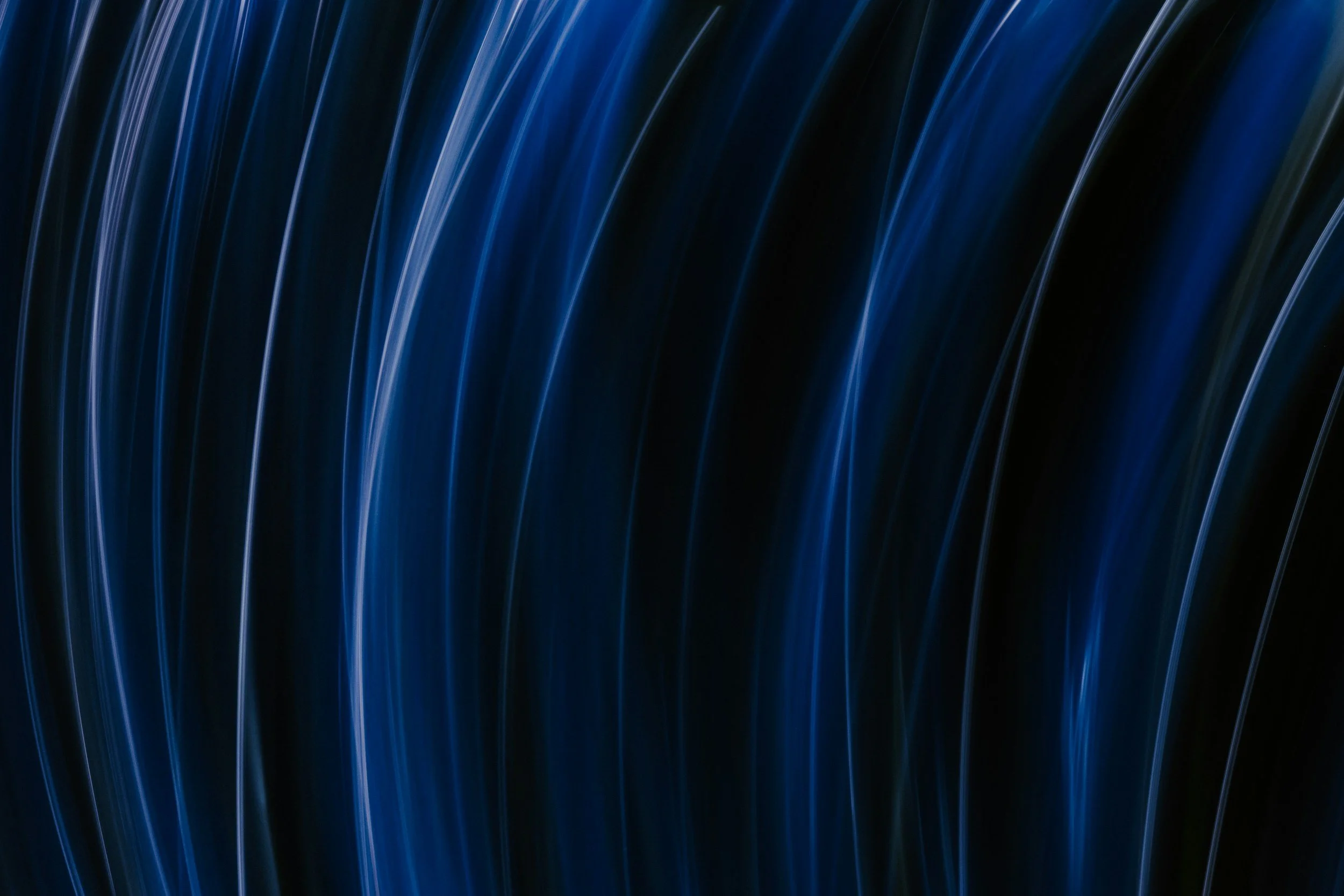 Abstract image of blue light trails in curved patterns on a black background.