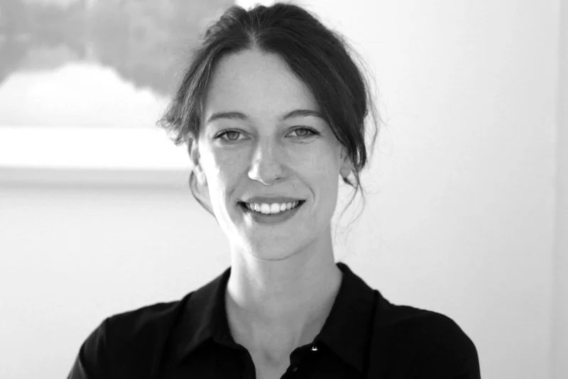 Black and white portrait of a woman with shoulder-length hair, smiling, wearing a collared shirt.