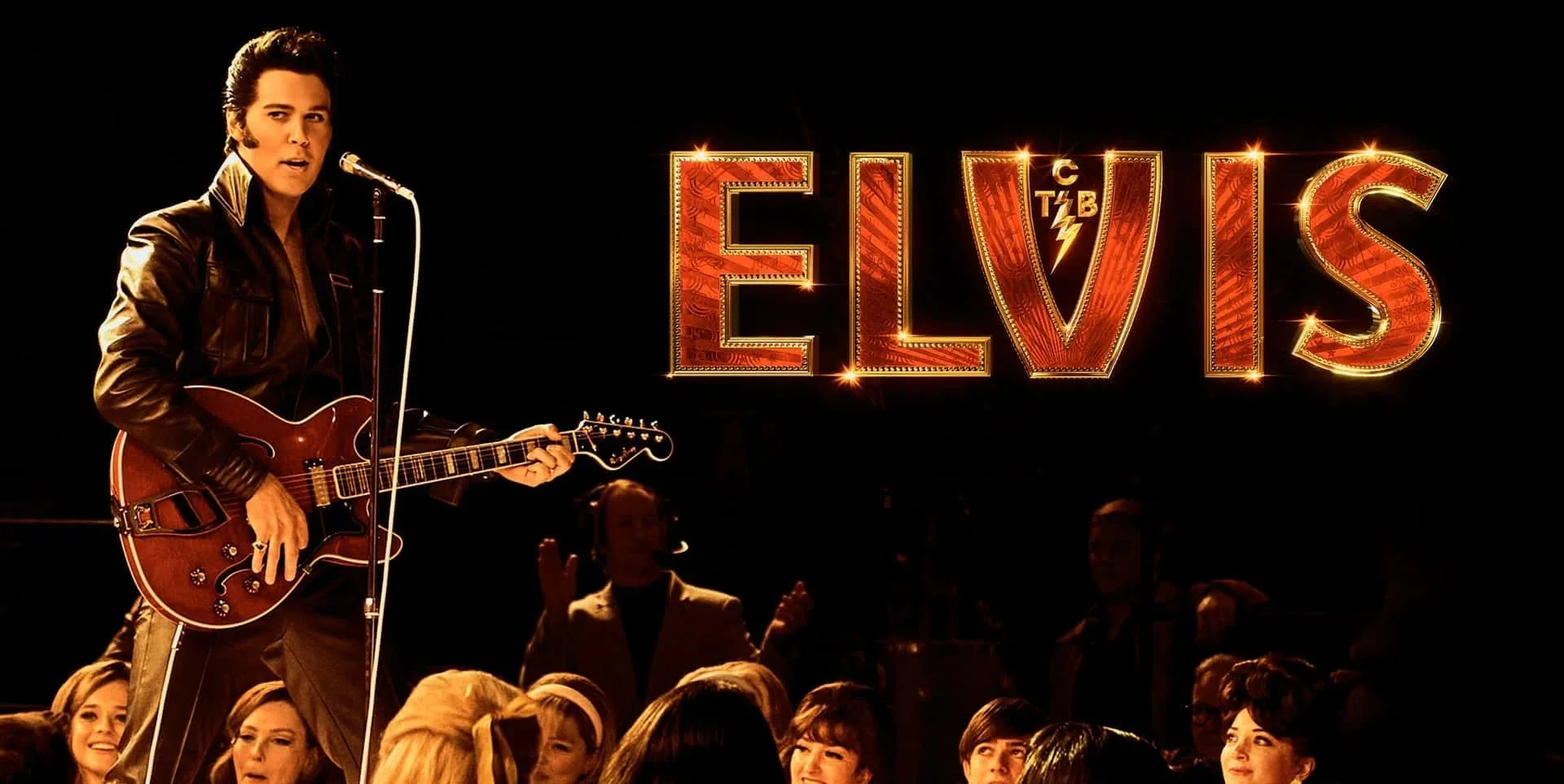 A scene from the movie 'Elvis' showing Elvis Presley singing and playing guitar on stage with a large illuminated sign spelling out 'ELVIS' in the background, surrounded by an audience.
