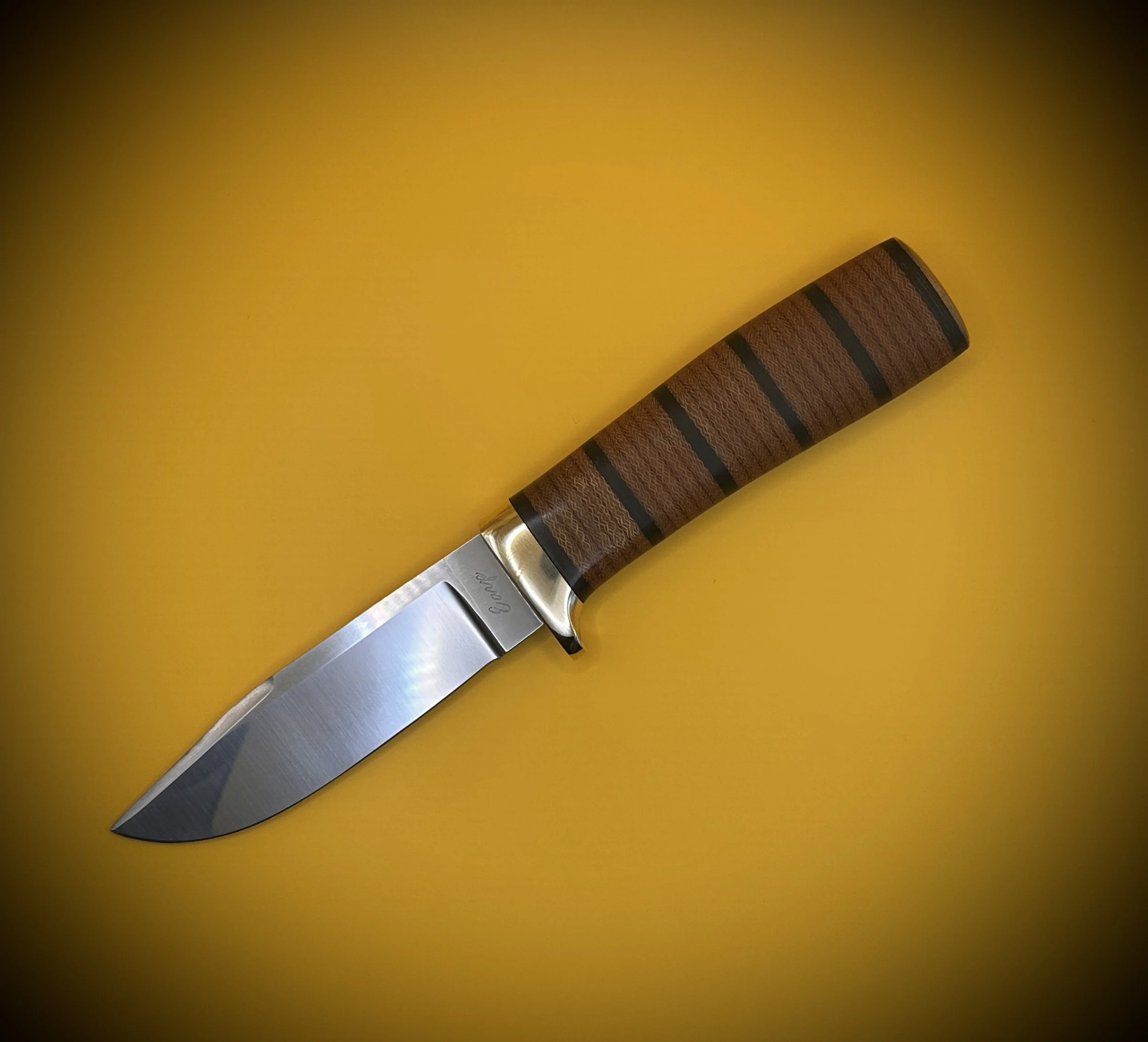 A kitchen knife with a wooden handle and a stainless steel blade on a yellow background.