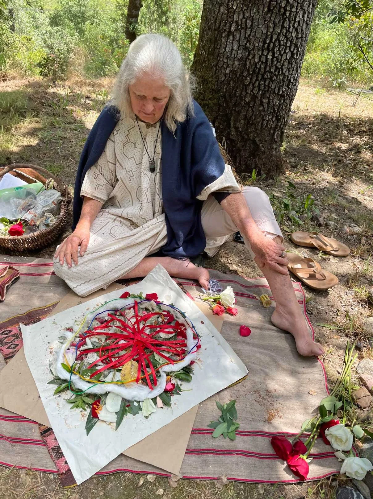 Shaman sitting in nature as she creates a mandala out of natural elements as earth medicine and wheel of life