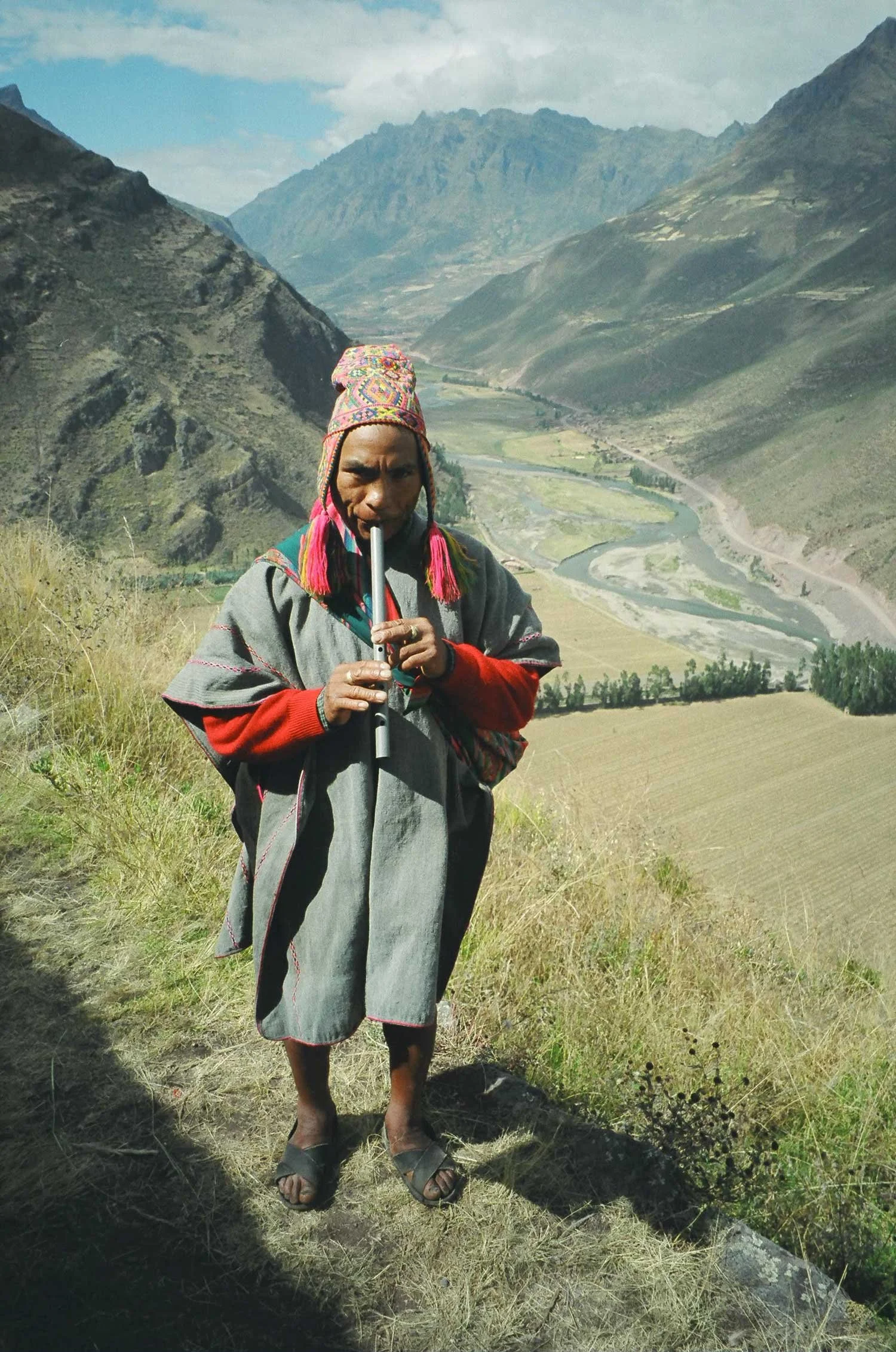 Andes mountains in the background with a Peruvian man playing a flute in the foreground
