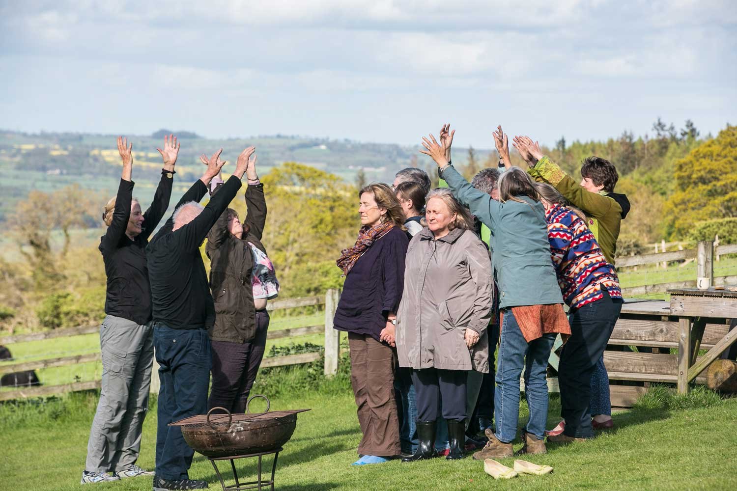 People gathered outside with their hands up to the sky as they pray together after drumming
