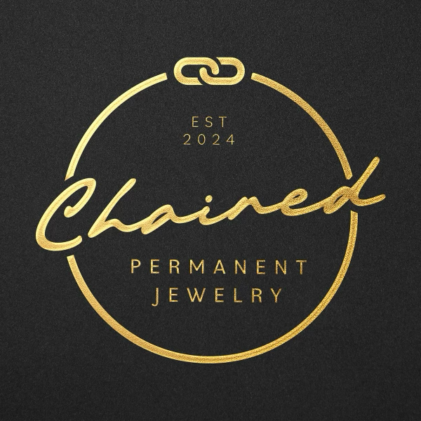 Gold logo on black background that reads "Chained Permanent Jewelry", with an oval outline and a chain link at the top, established in 2024.
