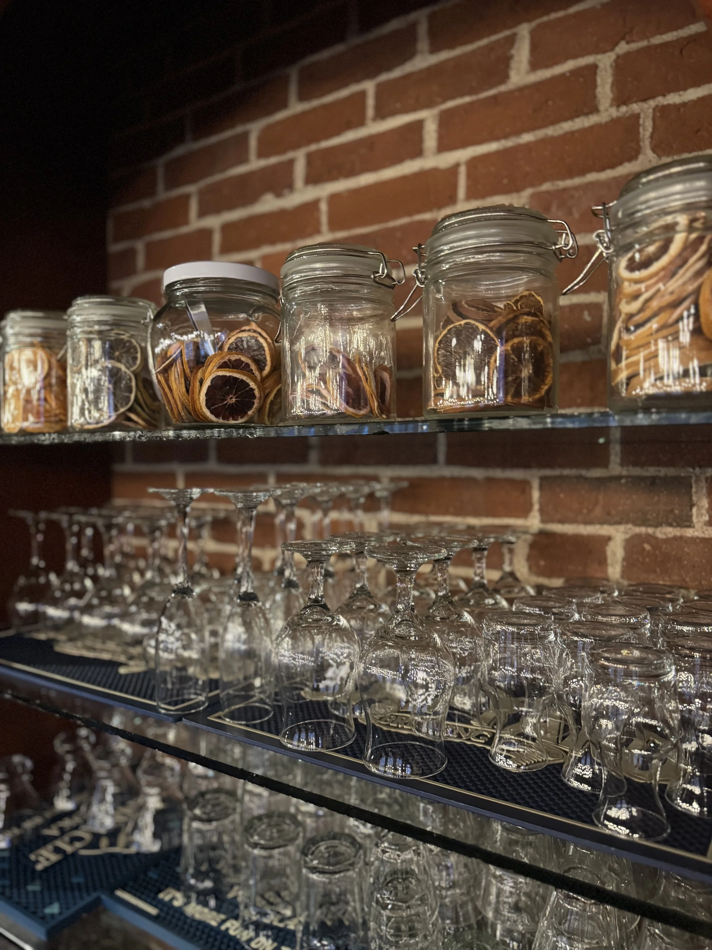 A gorgeous view of part of the bar at the waterworks in rockland Maine with beautiful jars of dried fruit and a display of different glasses