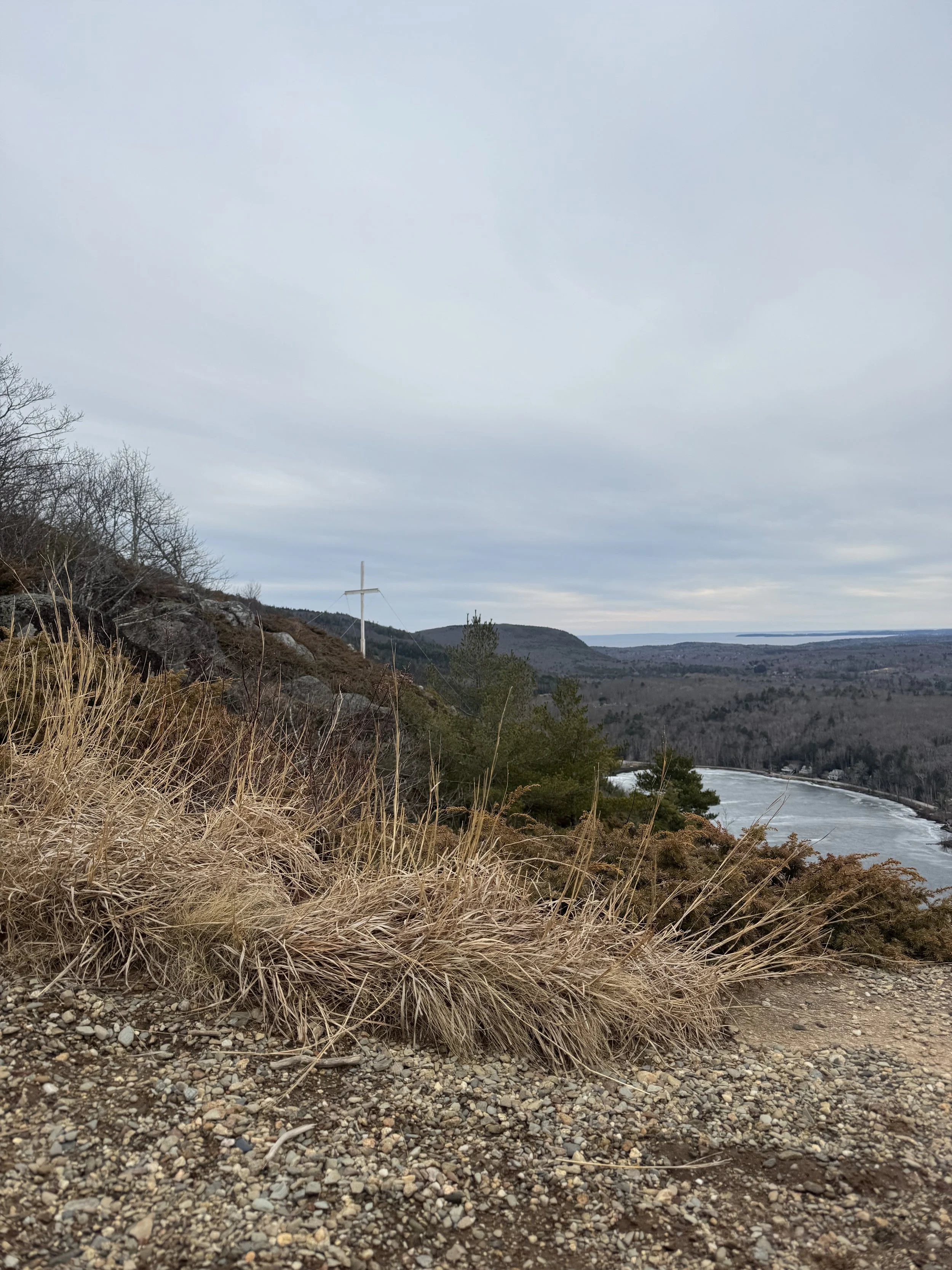 An amazing view at the maidens cliff Trail Peak with the iconic white cross overlooking Camden Harbor in the distance in Camden maine