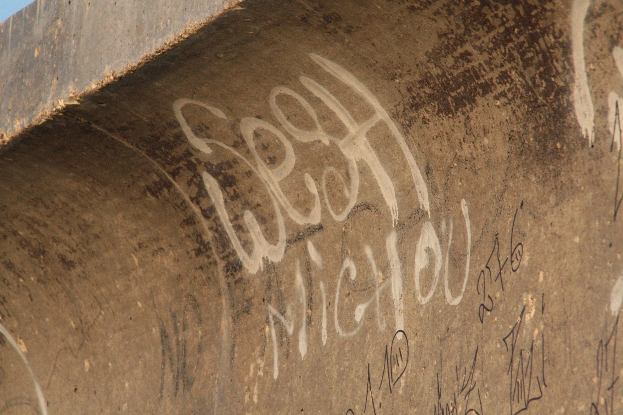 Graffiti spelling 'Baby Made Me Do It' written on a concrete tunnel wall.