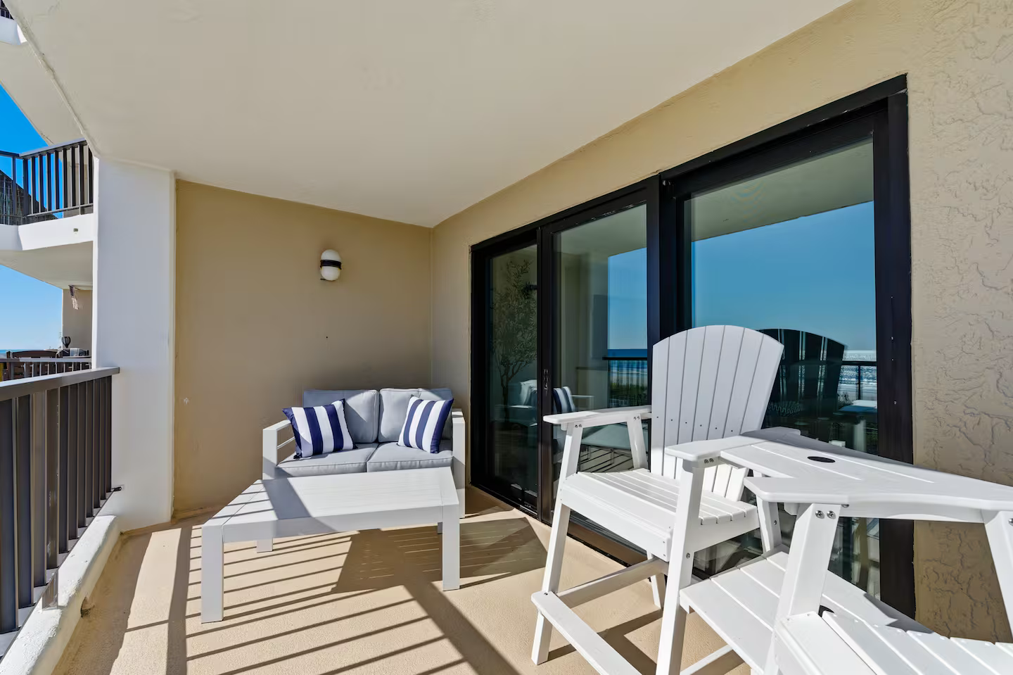 Relax on your private covered balcony featuring a comfortable loveseat with coastal-inspired accents. This shaded outdoor living space offers a perfect spot for morning coffee or evening cocktails with a view of the Atlantic.