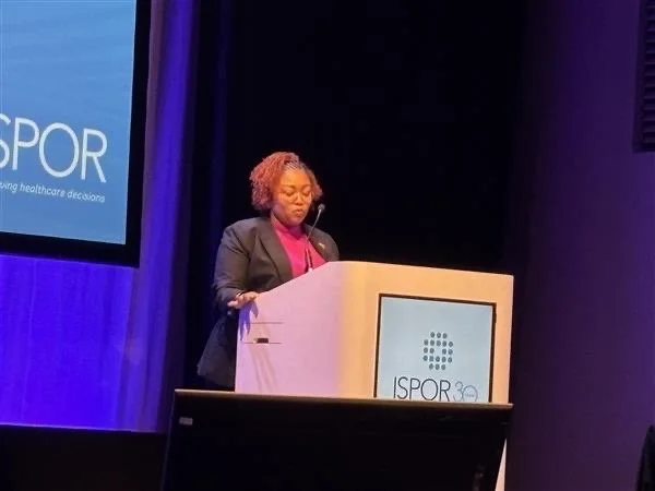 A woman standing at a podium giving a presentation at an ISPOR event.