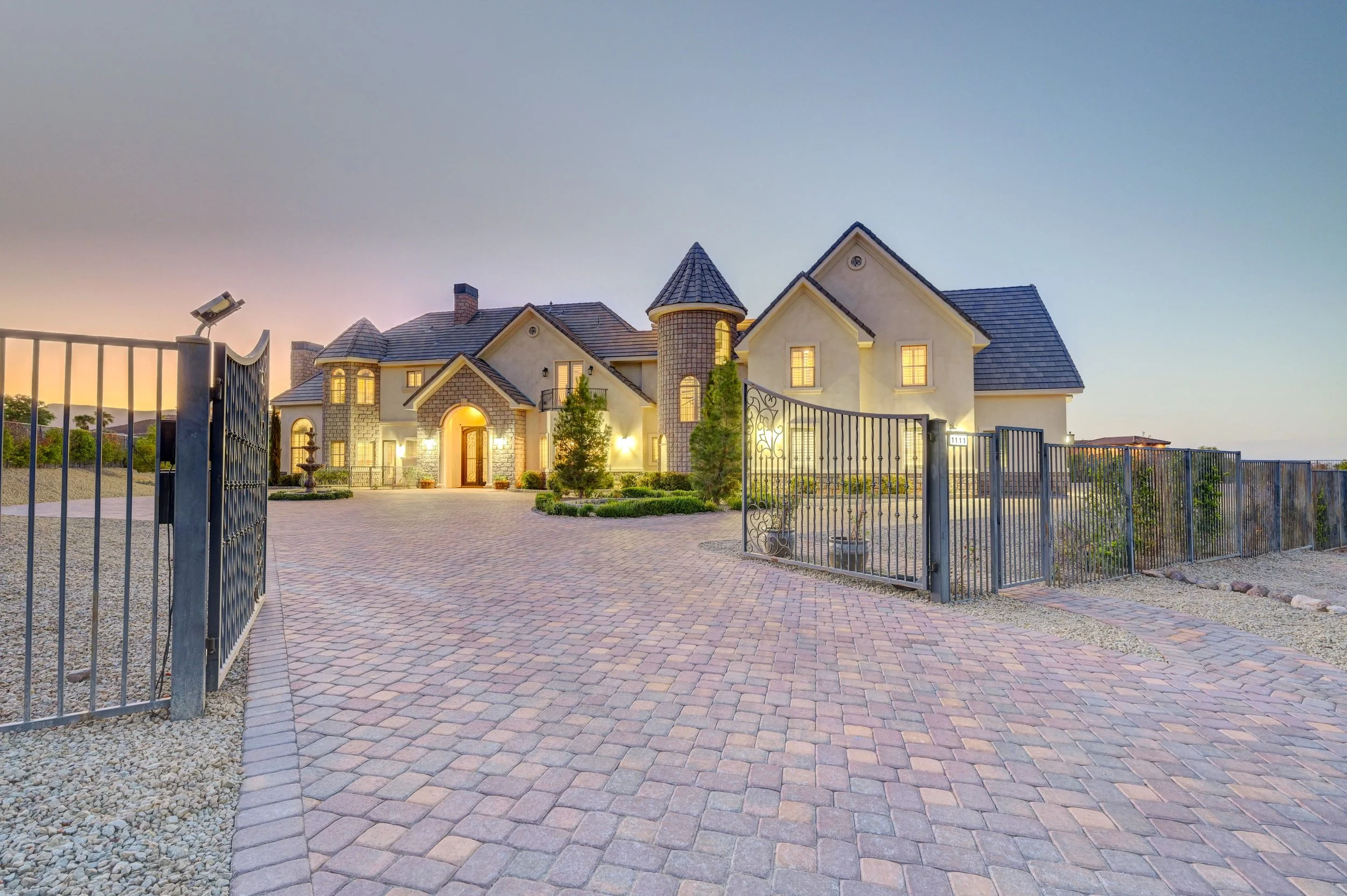Grand gated exterior of The Castle luxury vacation rental in Henderson near Las Vegas with landscaped front grounds at dusk