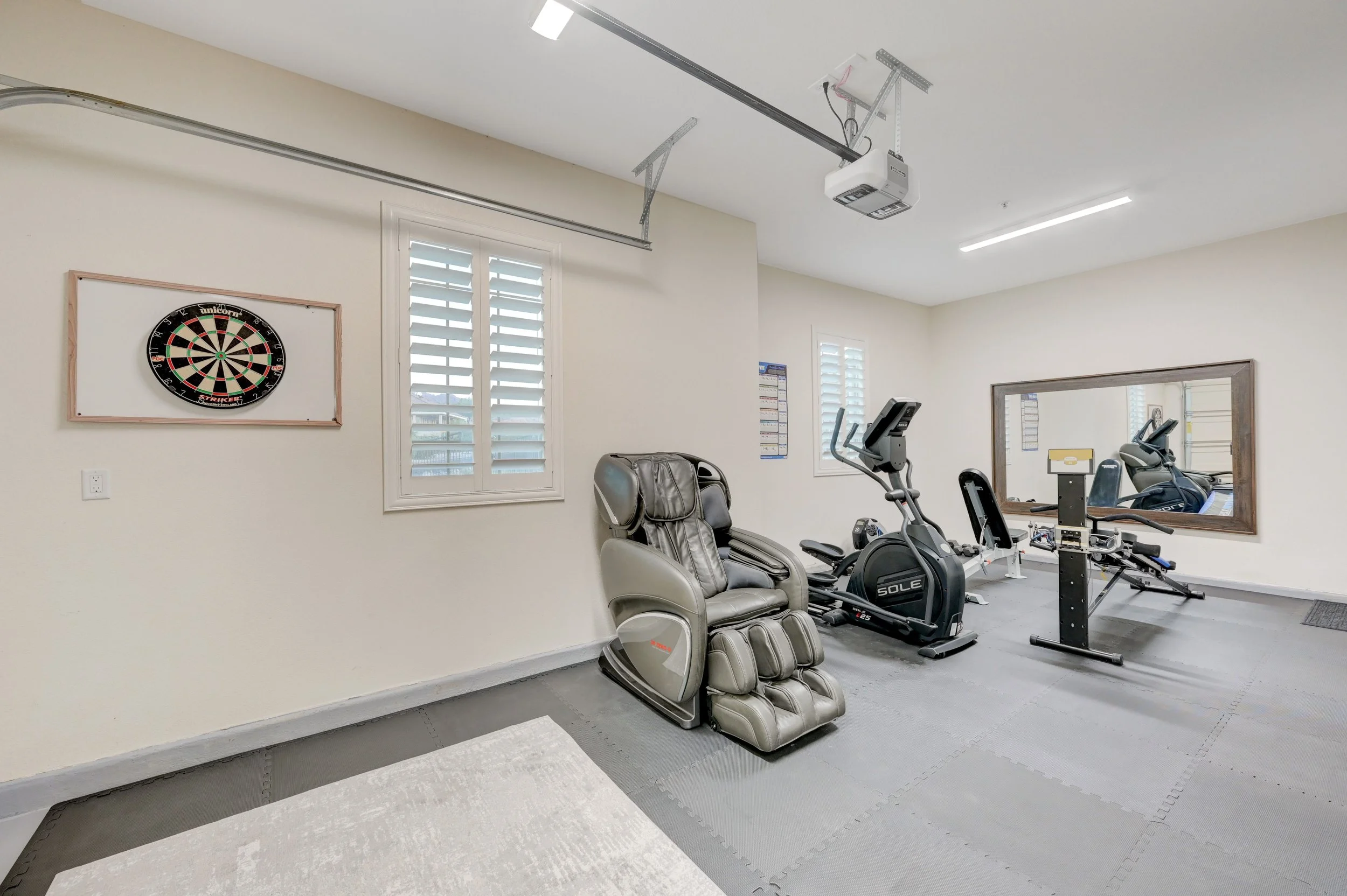 Private wellness studio with elliptical, stationary bike, workout bench, free weights, and massage chair at The Castle luxury vacation rental in Henderson near Las Vegas