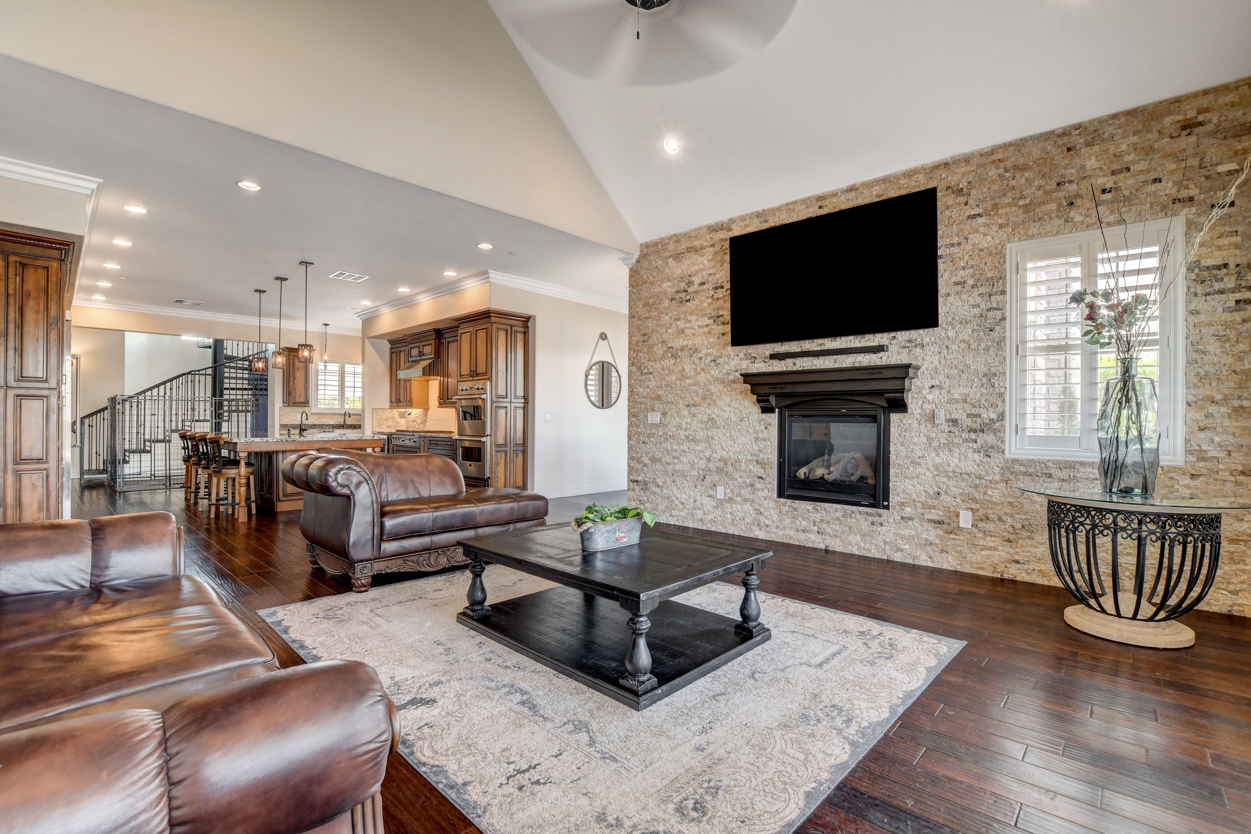 Open concept living room with fireplace and double doors to the pool, flowing into the gourmet kitchen with professional Viking appliances at The Castle luxury vacation rental in Henderson near Las Vegas