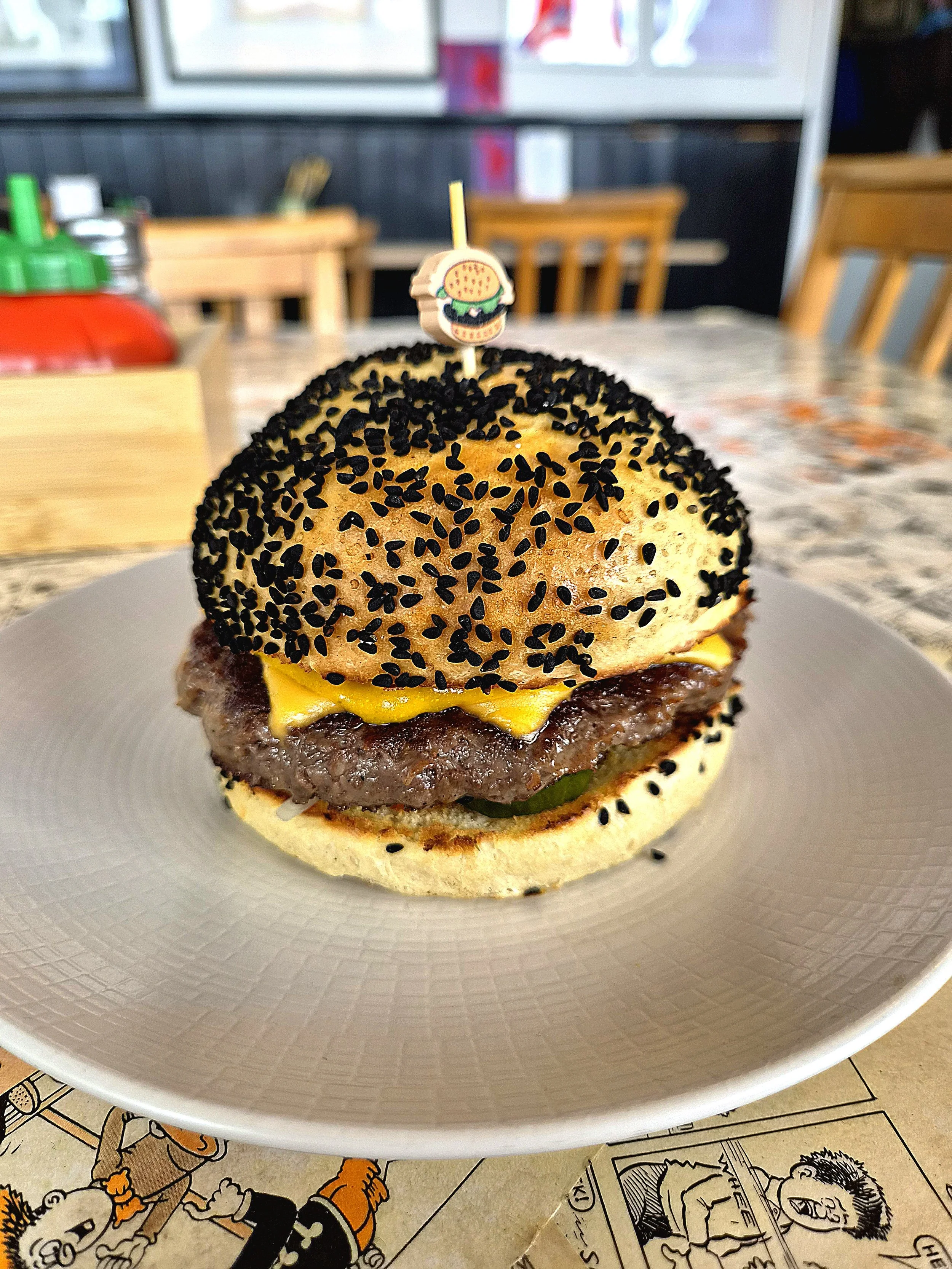 A cheeseburger served on a white textured plate in a casual restaurant setting.