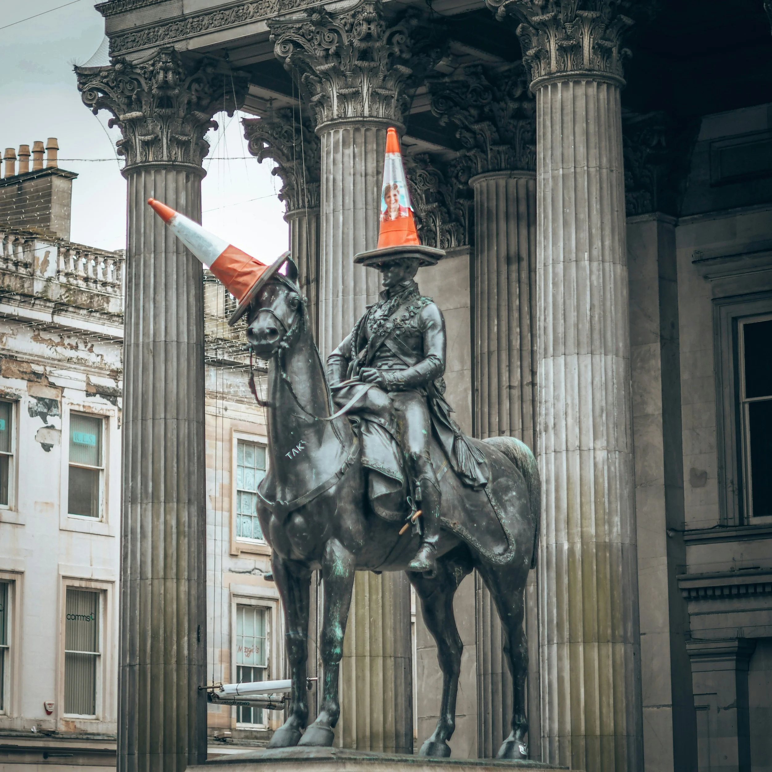Statue of a mounted soldier with orange and white traffic cones placed on the statue
