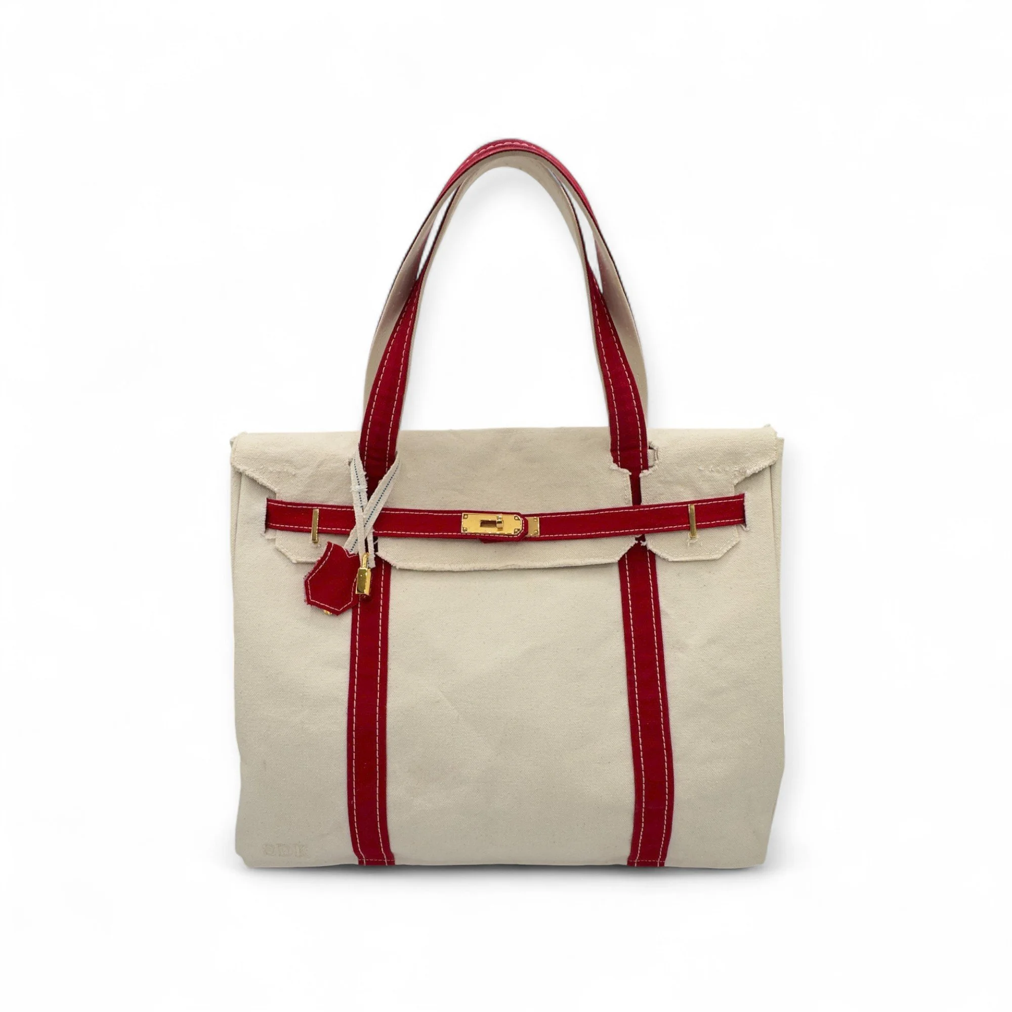 A Boatkin inspired bag up-cycled from an L.L. Bean vintage 1970's Boat and Tote.  Abeige handbag with red straps and a gold clasp, placed on a white background.