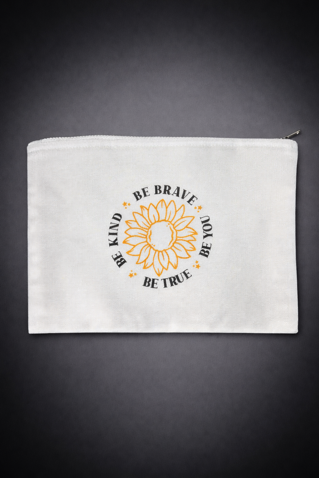 White zippered pouch with black and orange motivational quote and sunflower illustration on dark background.