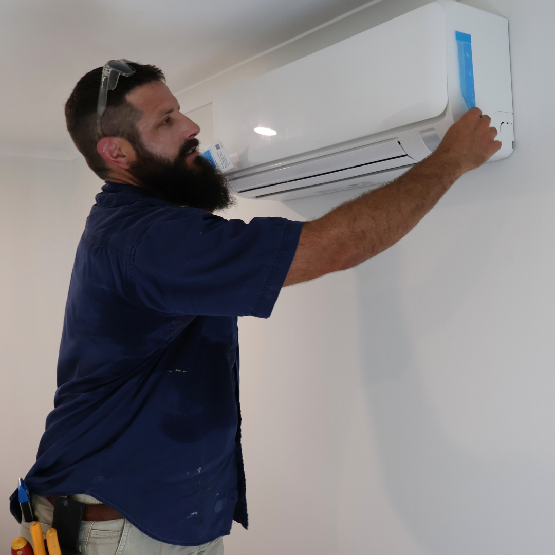 A man installing or repairing a wall-mounted air conditioning unit.