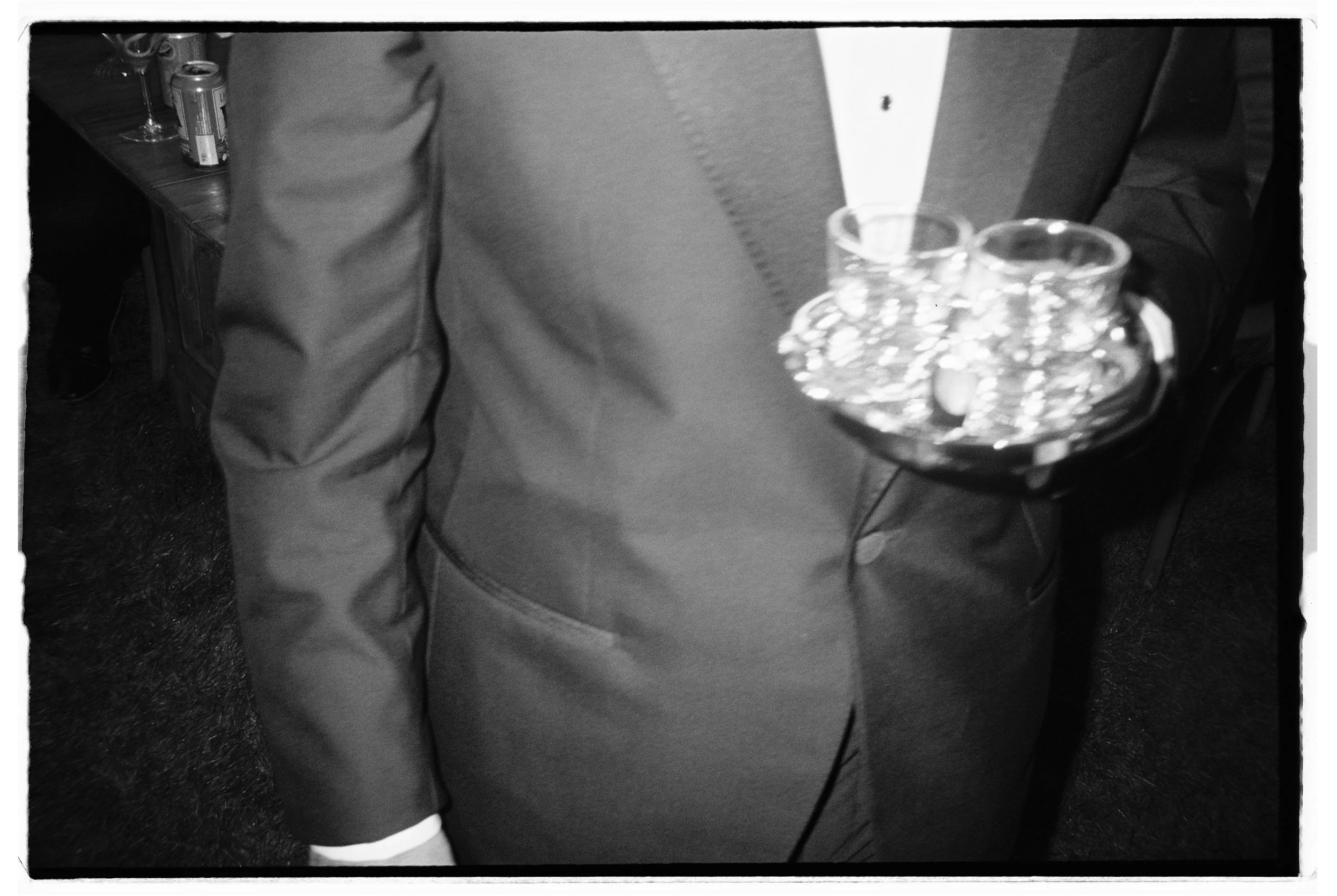 Person in a suit holding a tray with empty glasses at a formal event. Heritage House reception, Mendocino California. 