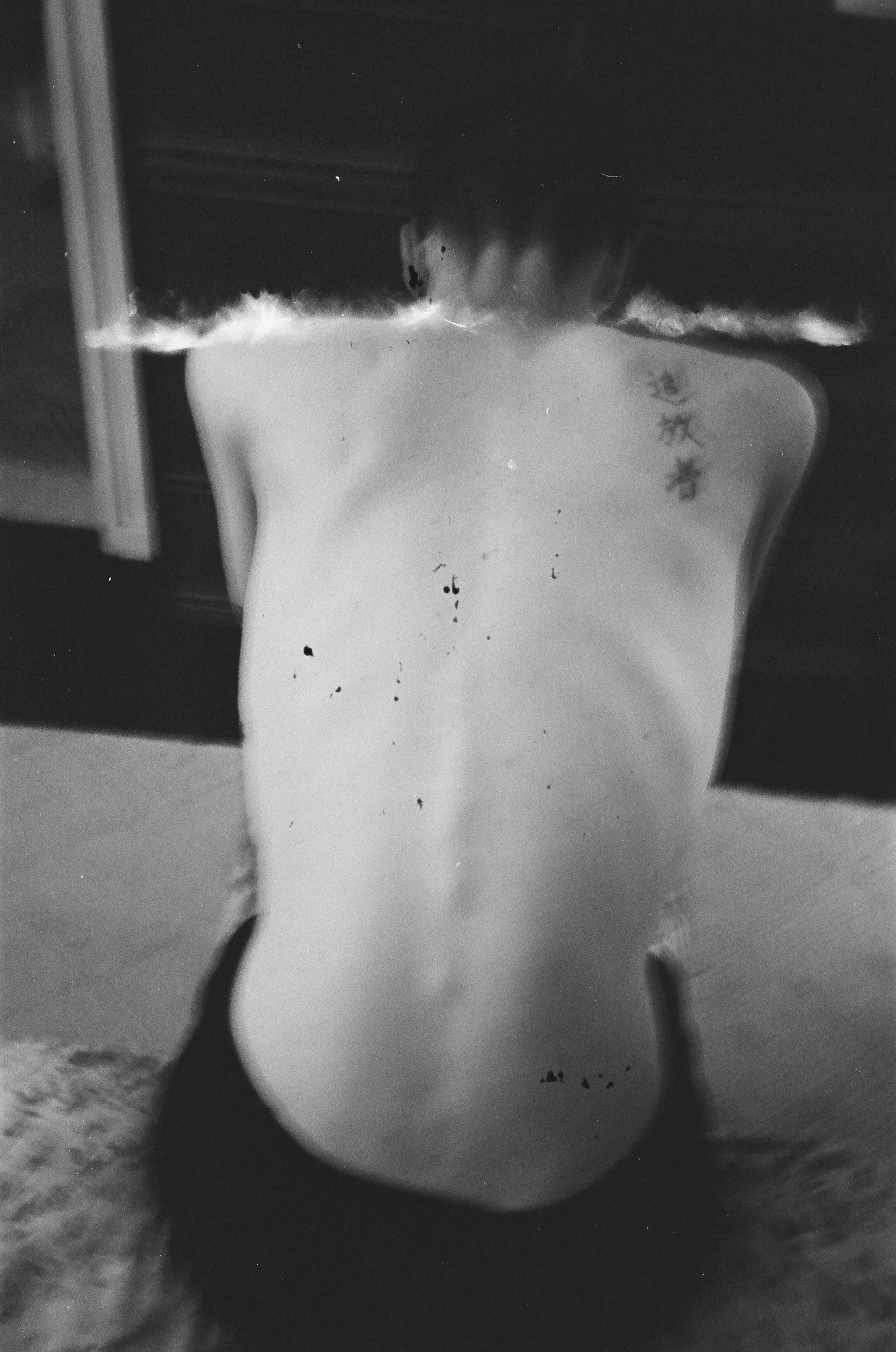 Black and white photo of a nude female torso with Asian characters tattooed on her left shoulder blade, facing away, with water or glass distortion affecting the image. Man on fire, film, tacoma Washington. 