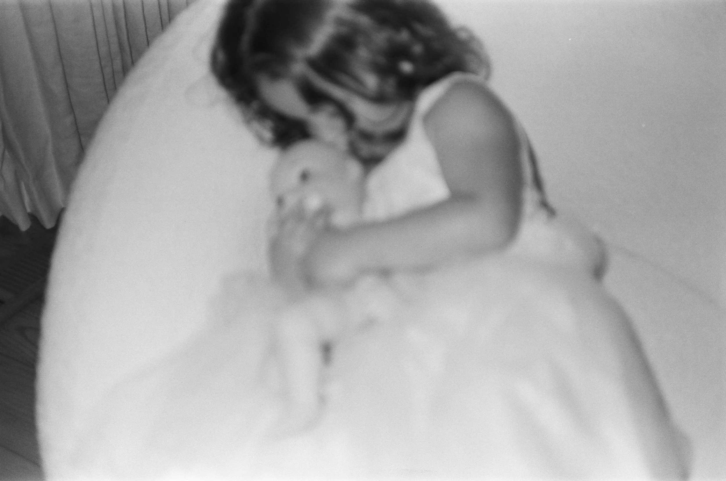 A young girl with patterned hair kisses a newborn baby wrapped in a blanket on a bed. Family photos Bay Area in film. 