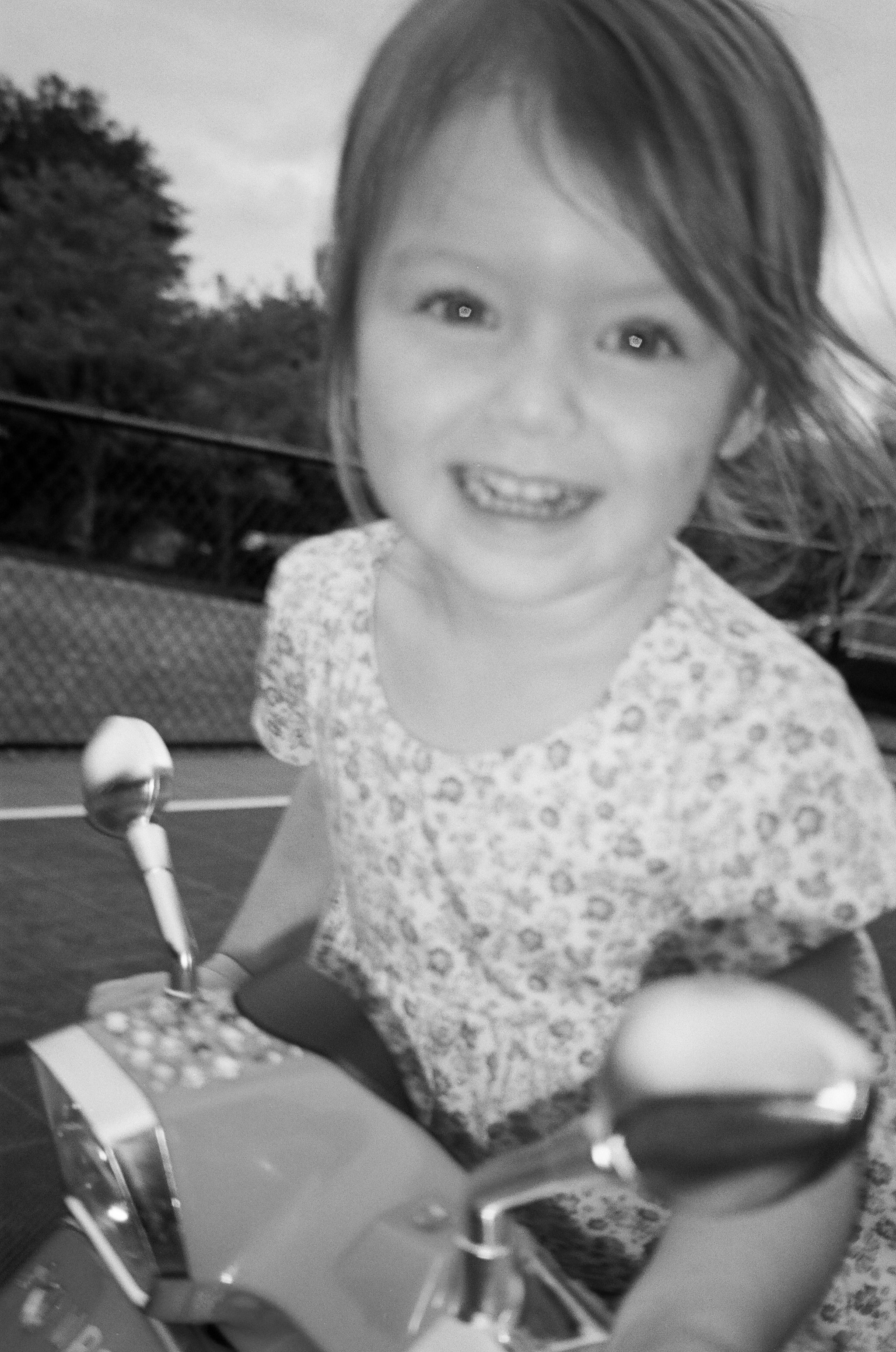 A smiling young girl with long hair riding a small motorbike outdoors.