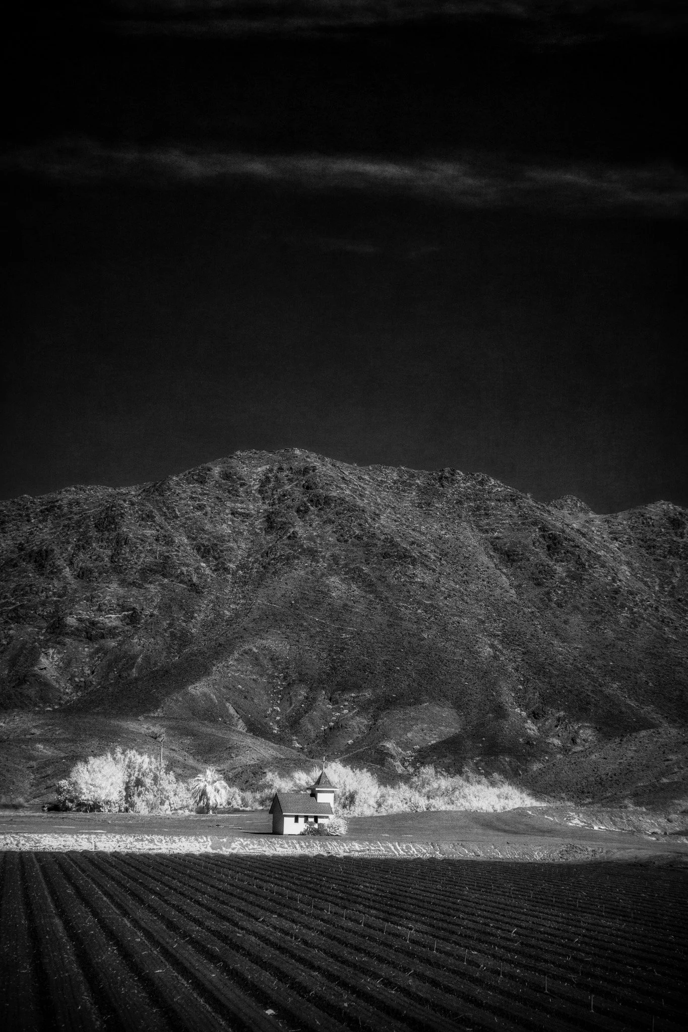 Yuma Arizona black and white infrared fine art print — isolated farmhouse with plowed field leading lines and dramatic desert mountain landscape