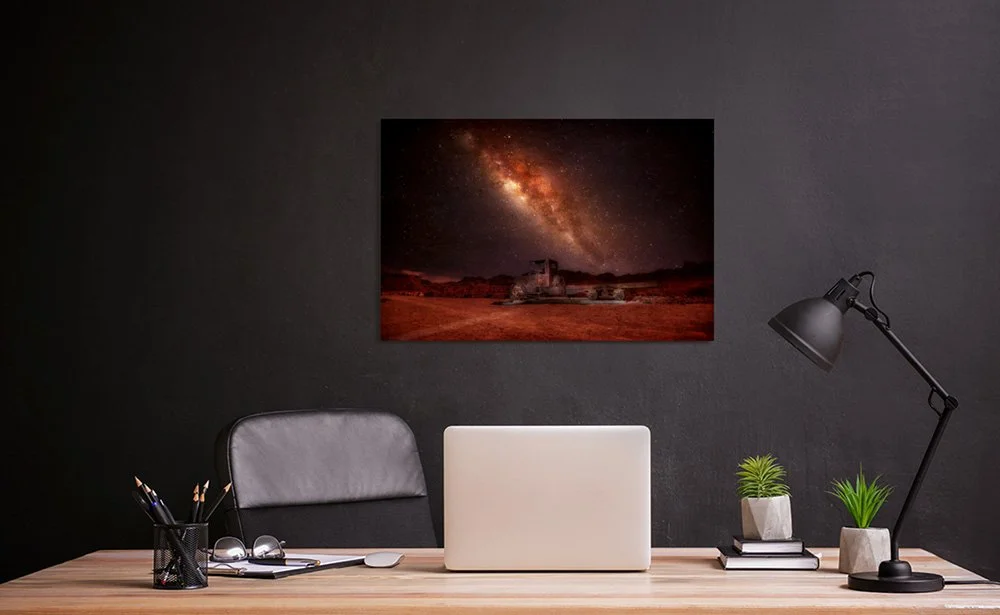 Night photo of the Milky Way over a desert landscape with an old vintage truck relic in the foreground under a star-filled sky.