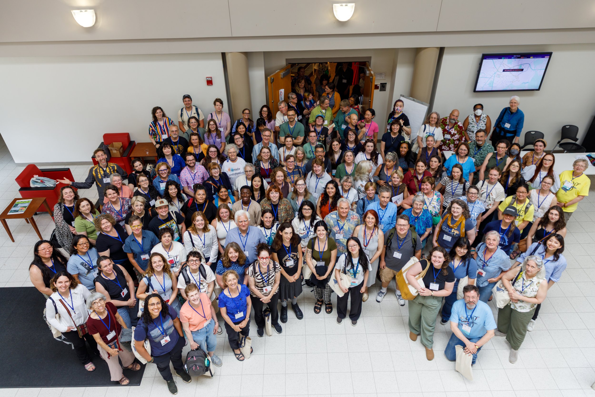 Group of diverse people gathered for a conference or event inside a large building.