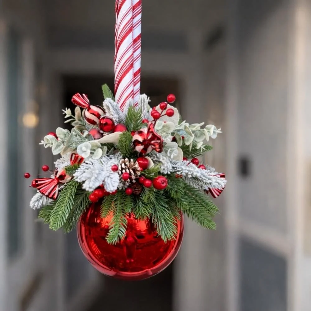 Christmas flower arrangement with red roses, greenery and festive details