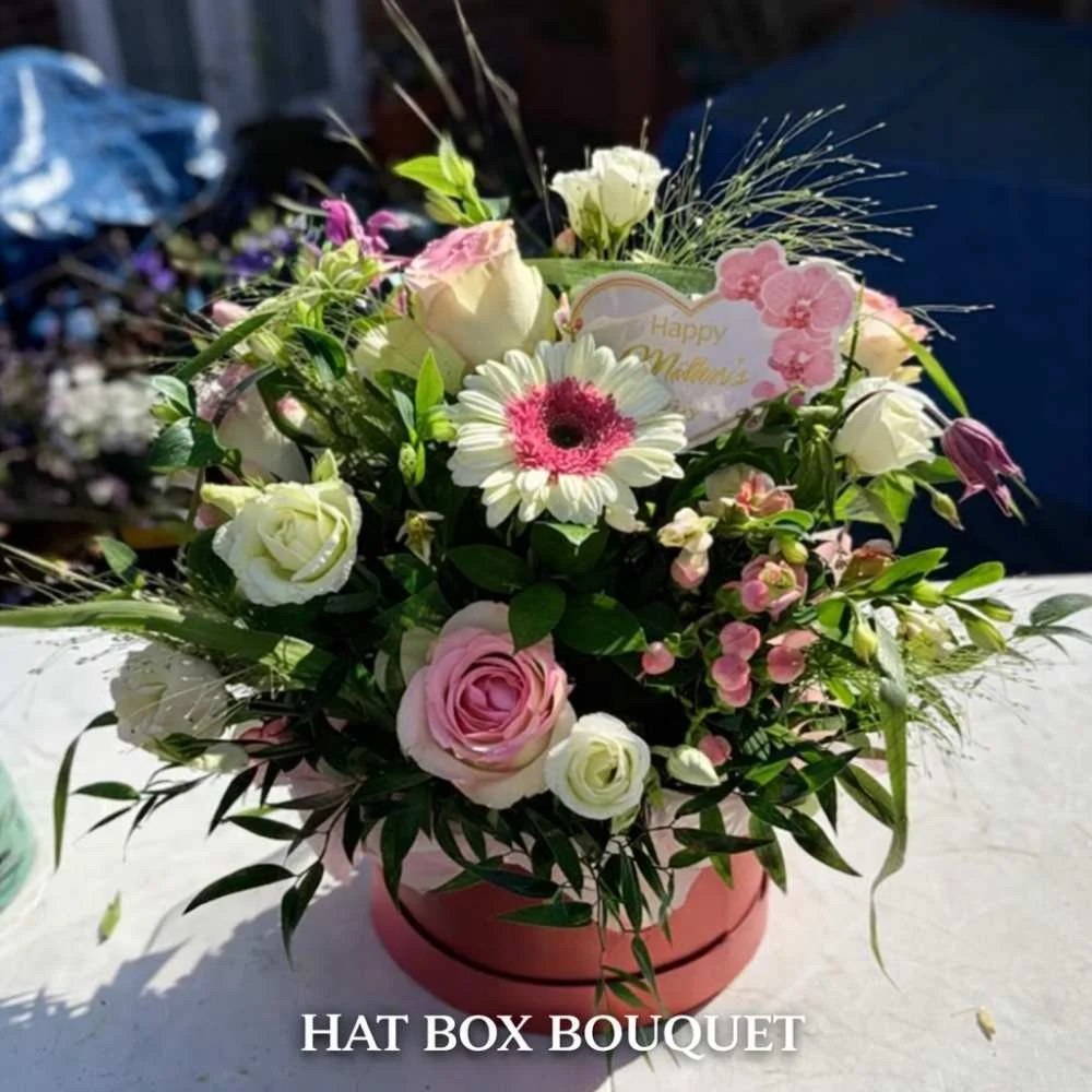 Red hay box containing pink and cream flowers