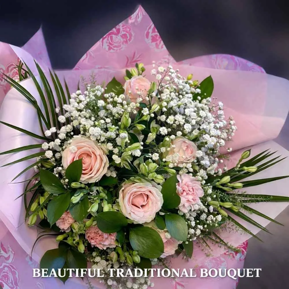 Bouquet of pink flowers in a traditional tissue paper wrapped bouquet