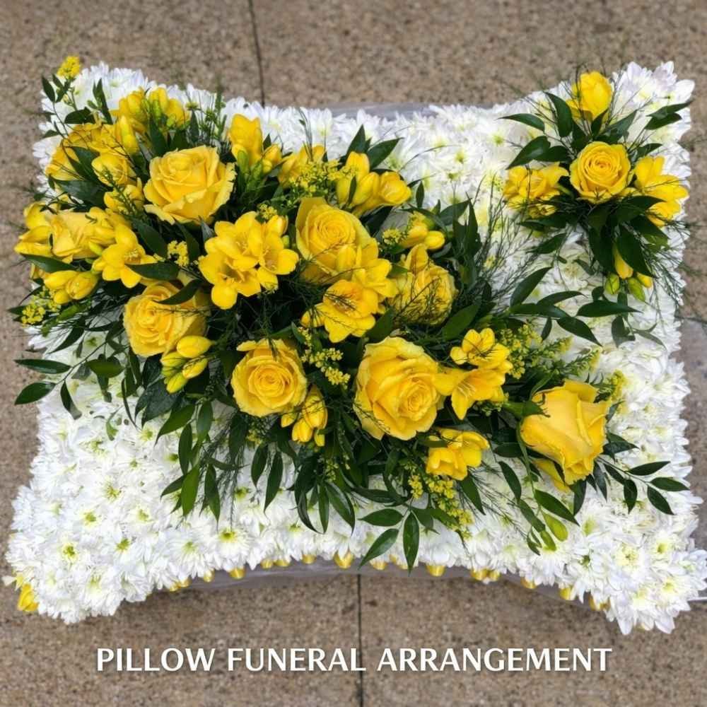 White flowers made into the style of a pillow with a stunning yellow flower arrangement on it