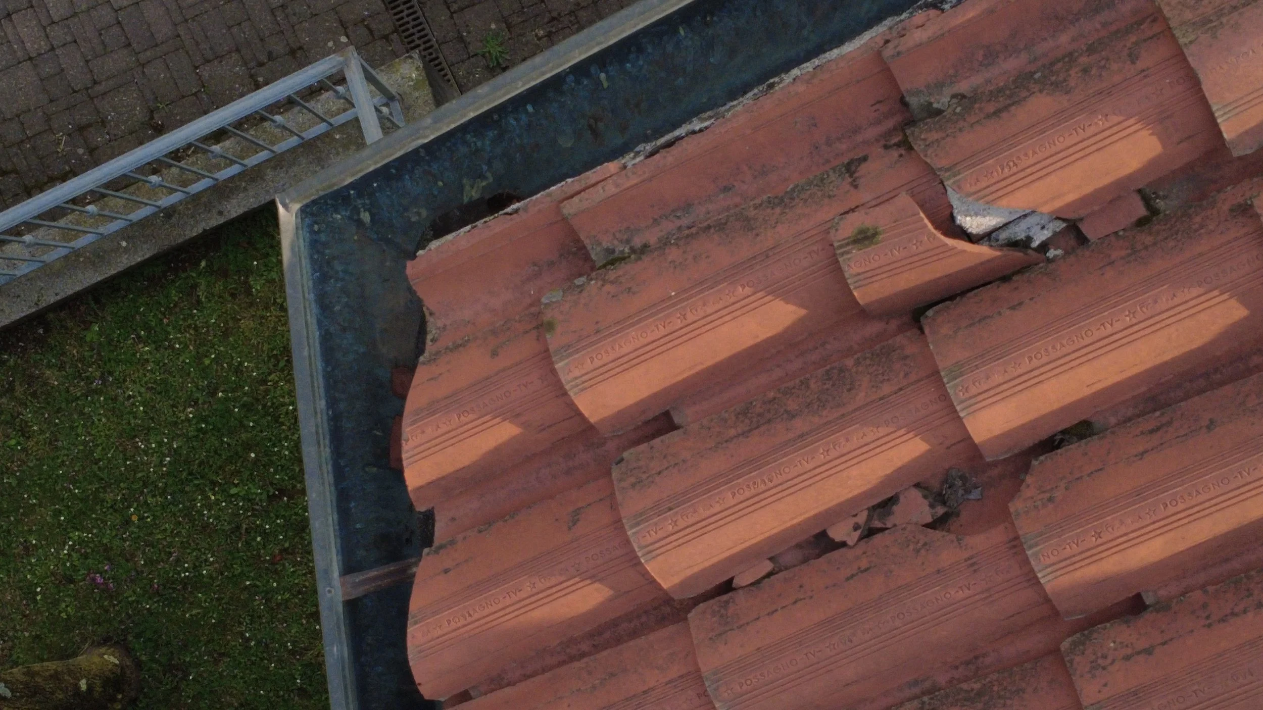 Dettaglio tecnico ispezione aerea copertura: rottura tegole e accumulo sporcizia nel canale di gronda, analisi post-inverno ALTO LIVELLO