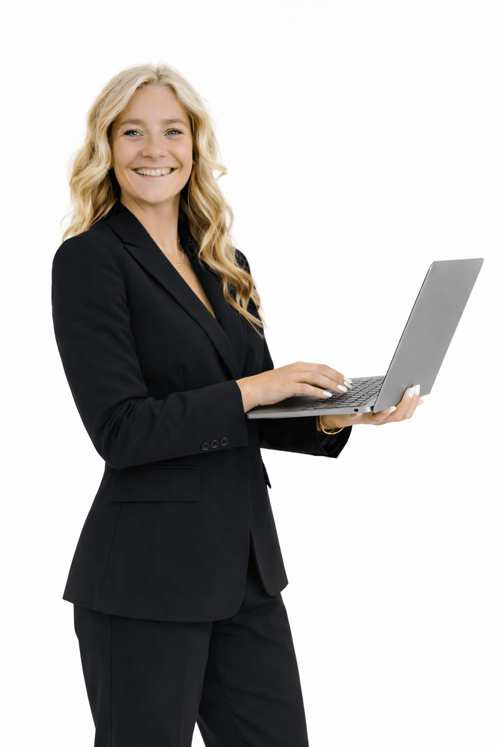A woman with long blonde hair in a black business suit holding a silver laptop, smiling at the camera.