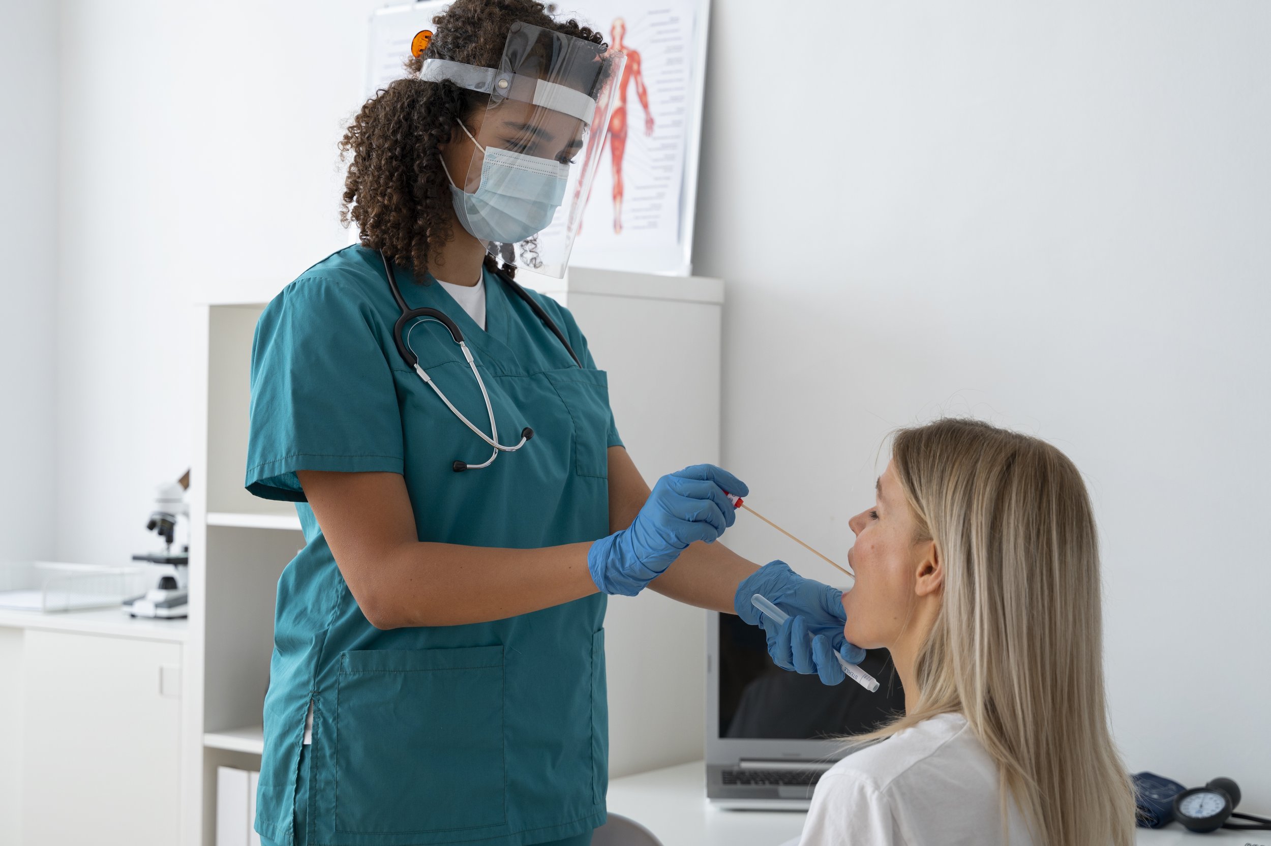 Healthcare professional administering a COVID-19 test to a woman in a medical office.