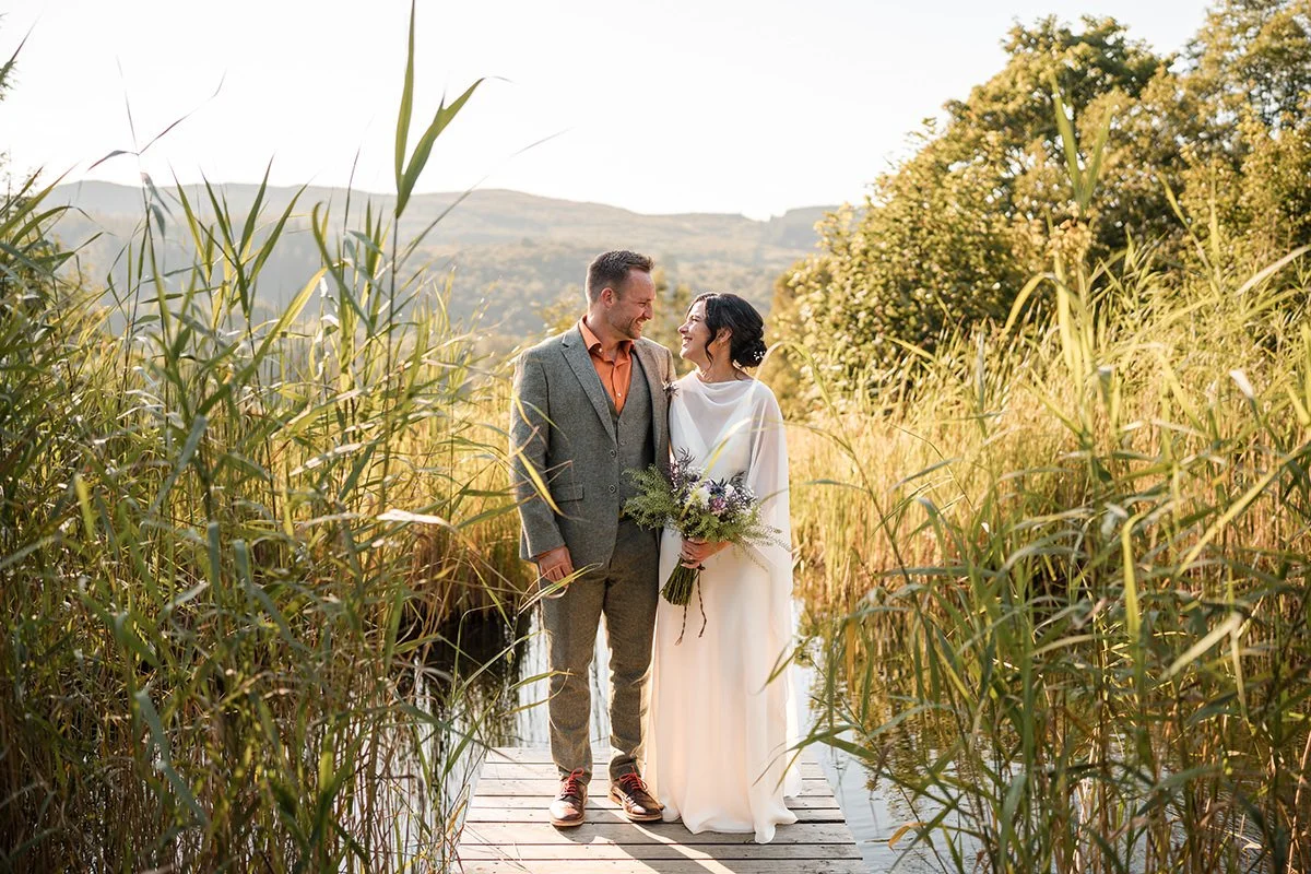 Couple standing on a wooden dock surrounded by reeds during their Kilmartin Castle elopement in Scotland.